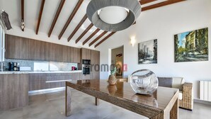 Une cuisine moderne avec des meubles en bois, un îlot central et un coin repas comprenant une table en bois et un saladier décoratif.