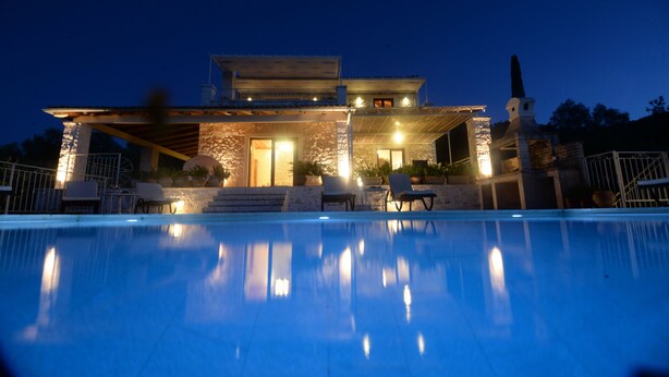 A modern house with a swimming pool, stone facade, and outdoor seating area.