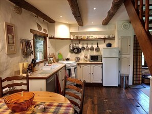 Une cuisine avec des poutres en bois, des meubles blancs, une cuisinière et un four à micro-ondes.