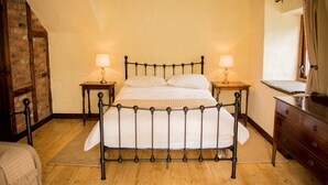 Ein traditionell eingerichtetes Zimmer mit einem Himmelbett, Holzböden und freiliegenden Backsteinwänden.