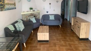 A living room with two sofas, a coffee table, a fireplace, and a TV mounted on the wall. - Lovely House - Pool/Garden/Wi-Fi - Casa Palmera (L'Escala)