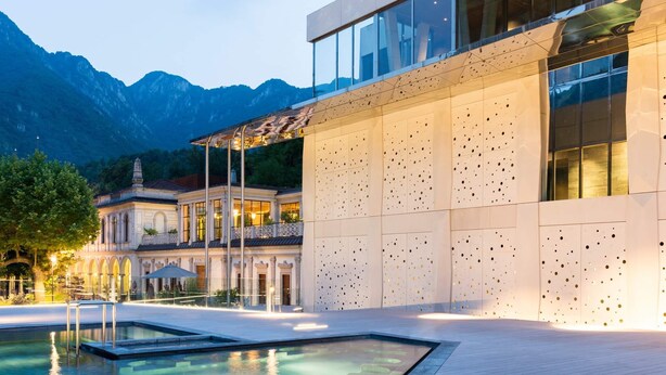 A modern building with a pool, a traditional building in the background, and mountains in the distance. - Design seashell design (San Pellegrino terme bergamo)