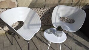 Two white chairs with metal legs and a small white table with a glass bowl and a potted plant. - Design seashell design (San Pellegrino terme bergamo)