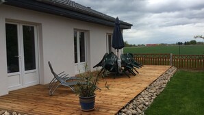 A covered patio with outdoor furniture, a wooden deck, and a stone border. - 3-bedroom house near Colmar (Bennwihr)
