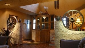 A rustic interior with a stone fireplace, wooden furniture, and decorative wheels. - Eras de Pantrillar Rural House (full rental) for 10 people (Ciruelas)
