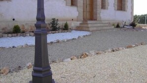 A building with a symmetrical facade, a central entrance with a door, and a gravel driveway. - Eras de Pantrillar Rural House (full rental) for 10 people (Ciruelas)