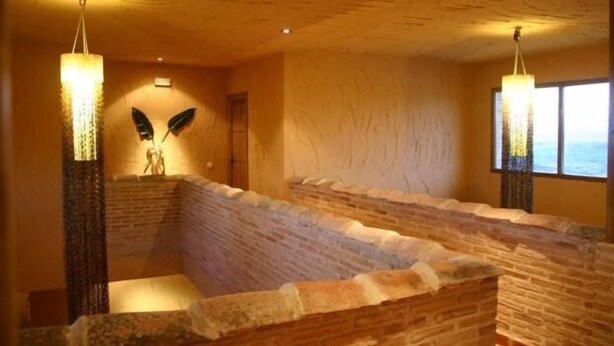 A spa area with stone walls and a seating area. There are two large, illuminated columns and a window with a view. - Eras de Pantrillar Rural House (full rental) for 10 people (Ciruelas)