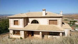 A two-story house with a tiled roof, arched windows, and a chimney. - Eras de Pantrillar Rural House (full rental) for 10 people (Ciruelas)