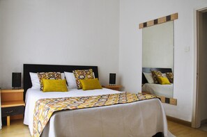 Une chambre à coucher bien rangée, avec un lit, des tables de chevet et un grand miroir.