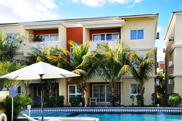 Un hôtel doté d’une piscine, de palmiers et d’un espace salon abrité.