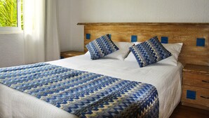Una cama bien hecha con una colcha estampada, dos almohadas y un cabecero de madera.