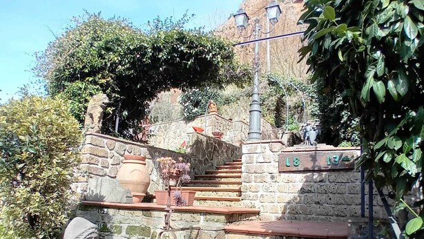 A stone staircase with terracotta steps leading up to a stone wall.