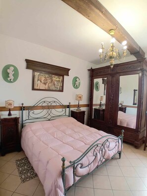 Una camera da letto con un letto, una testiera in legno, un lampadario, uno specchio e un quadro appeso alla parete.