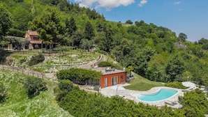 Une propriété située sur une colline, dotée d’une piscine, d’un bâtiment rouge et d’une grande maison.