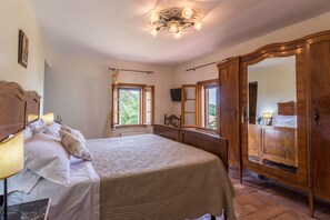 A bedroom with a bed, a wooden wardrobe, a mirror, and a window with a view of greenery. - Villa Ise by Anita Villas (Montefelcino)