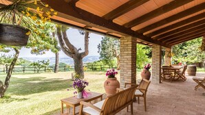 Une terrasse extérieure avec des meubles en bois, une plante suspendue et une vue sur le paysage.