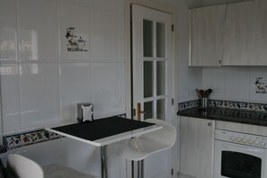 A kitchen with white cabinets, a black countertop, and a white chair.