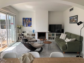 A modern living room with a sofa, chairs, a fireplace, and a television.