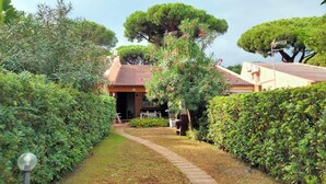 Un chemin menant à un bâtiment dont le toit est recouvert de tuiles, entouré de haies et d’arbres bien entretenus.