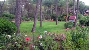 Un parc équipé d’aires de jeux, d’arbres et d’un petit bâtiment.