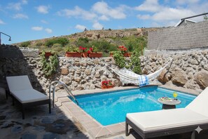 A pool with lounge chairs, a hammock, and potted plants. - Charming Rural House Las Perez in Tenerife South: Scenic Accommodation (Granadilla de Abona)