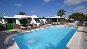 A swimming pool with lounge chairs, umbrellas, and a clear blue sky.