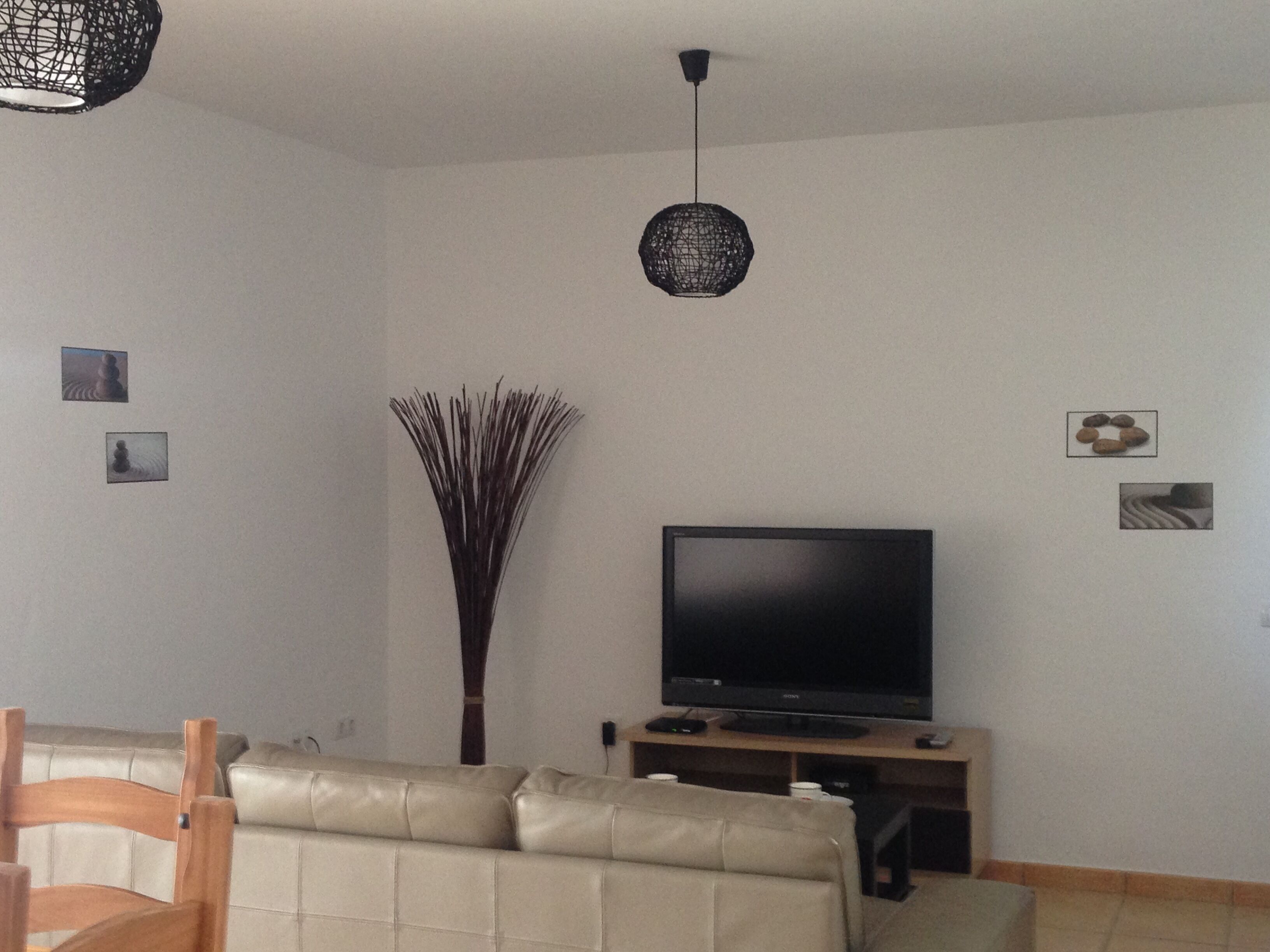 Een woonkamer met een bank, een flatscreentelevisie en een decoratieve vaas.