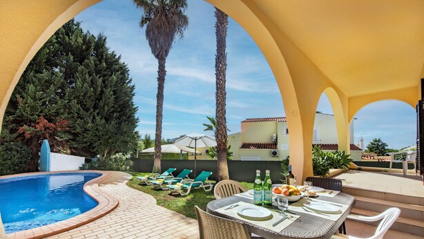 A poolside area with a dining table, chairs, and a pool. - Exclusive Retreat in Vilamoura, private pool, off-street parking, Free AC & wifi (Vilamoura)