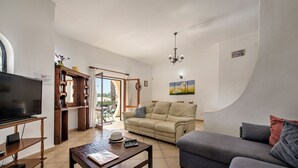 A living room with a television, sofa, coffee table, and a bookshelf. - Exclusive Retreat in Vilamoura, private pool, off-street parking, Free AC & wifi (Vilamoura)