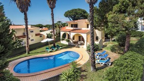 A pool area with a curved pool, lounge chairs, and a building with arches. - Exclusive Retreat in Vilamoura, private pool, off-street parking, Free AC & wifi (Vilamoura)