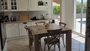 Una cocina moderna con armarios blancos, una mesa de comedor de madera y un gran ventanal con vistas a un balcón.