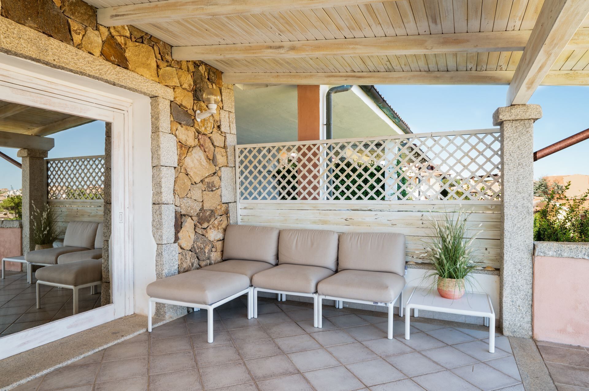 A covered outdoor seating area with stone walls and a wooden ceiling.