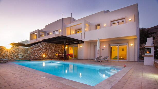 Una villa moderna con piscina, area relax esterna e muro in pietra.