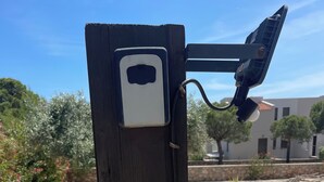 Un palo di legno con un dispositivo montato, probabilmente una telecamera di sicurezza, e una ringhiera metallica.