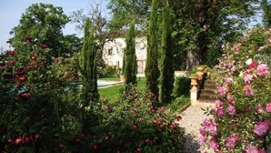 A garden with a pool, tall trees, and a building in the background. - Beautiful house with swimming pool, in Little Tuscany between Albi and Toulouse (Ambres)