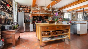 A rustic kitchen with exposed wooden beams, copper cookware, and a central island with baskets. - Beautiful house with swimming pool, in Little Tuscany between Albi and Toulouse (Ambres)