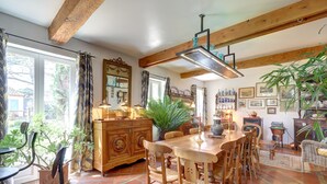 A dining area with a wooden table and chairs, a large plant, and a vintage-style cabinet. - Beautiful house with swimming pool, in Little Tuscany between Albi and Toulouse (Ambres)