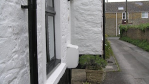 A narrow street with a white building featuring a black window frame and a white door. - Characterful 18th century cottage in Bridport close to the Jurassic Coast. (Bridport)
