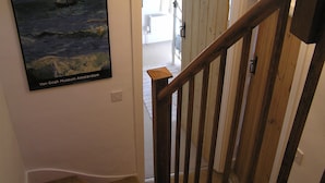 A staircase with wooden railings leading to a room with a white door and a painting of a sailboat on the wall. - Characterful 18th century cottage in Bridport close to the Jurassic Coast. (Bridport)
