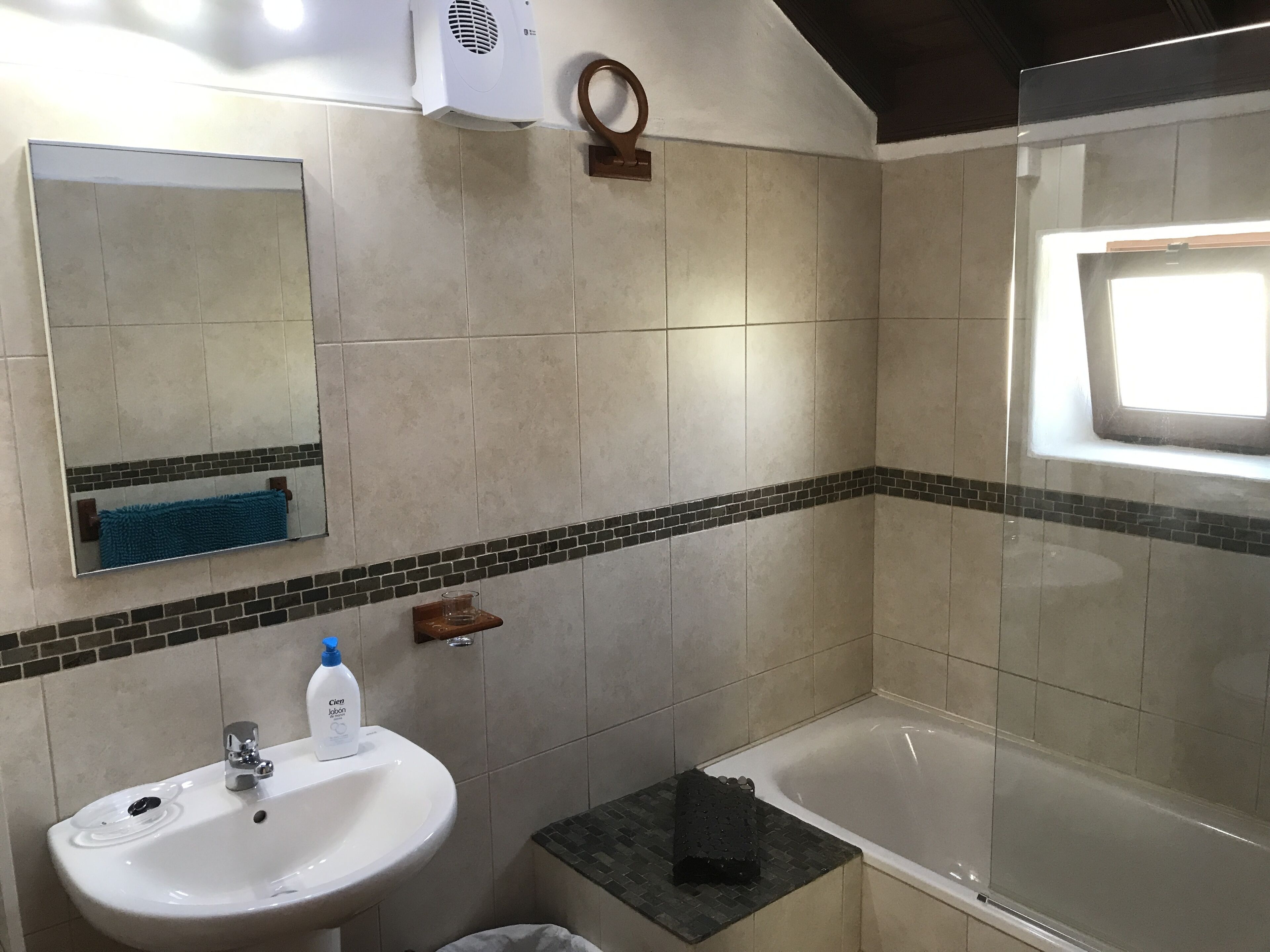 Een badkamer met een wastafel, spiegel en bad.