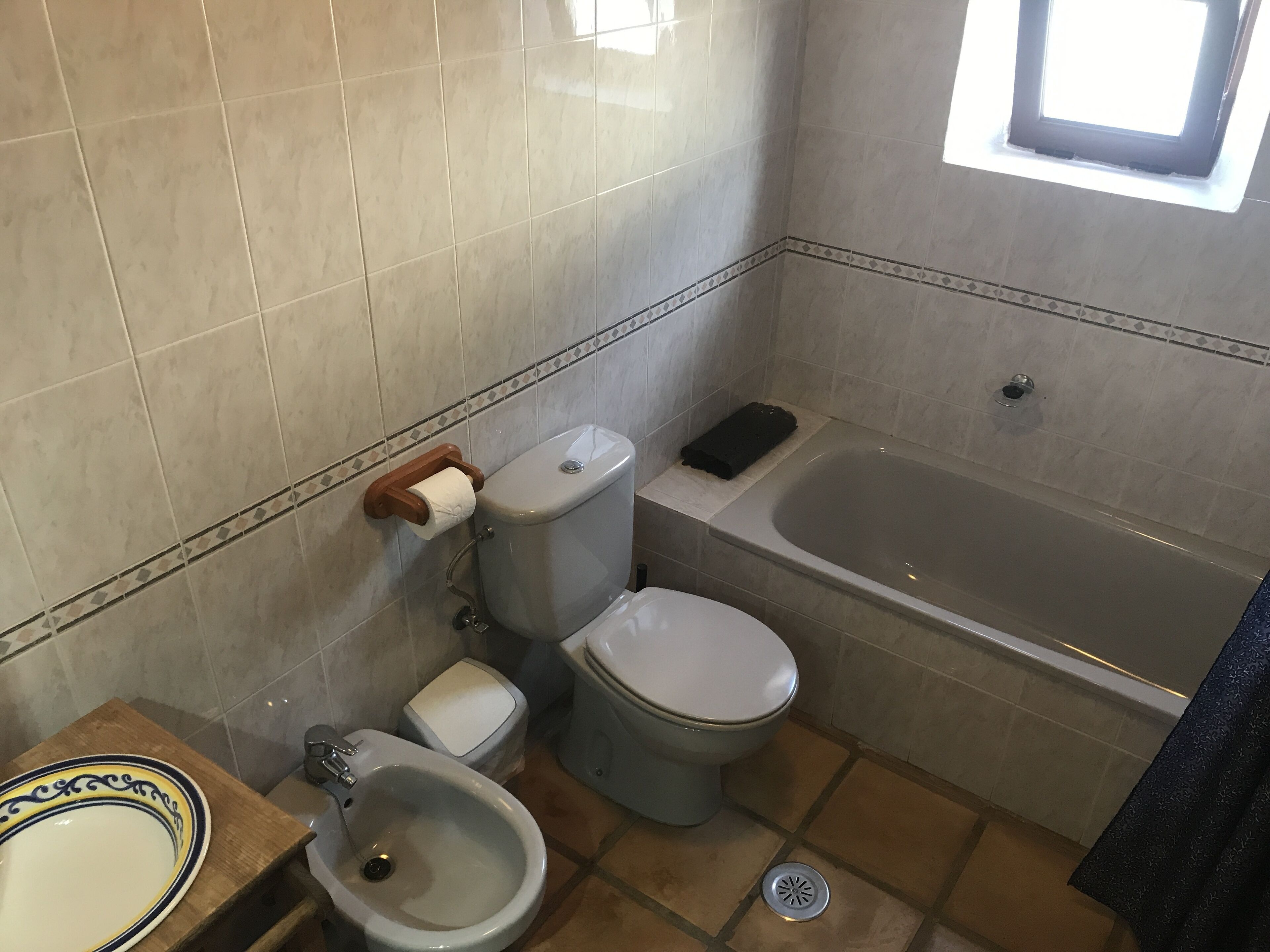 A bathroom with a toilet, bidet, bathtub, and a sink with a decorative basin.