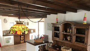 Una cocina rústica con armarios de madera, un lámpara colgante y suelo de baldosas.