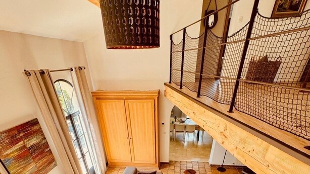 Un salon spacieux avec un grand canapé d’angle gris, une table basse en bois et un luminaire suspendu.