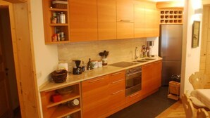Uma cozinha compacta com armários de madeira, geladeira de aço inoxidável e forno embutido.