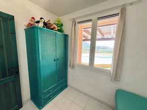 A room with a teal wardrobe, a window with a view of a pool and mountains, and a door. - Villa with private swimming pool for exclusive use - Chia - domus de maria (Chia)