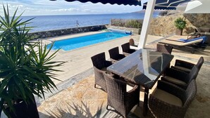 A poolside area with a view of the sea, outdoor furniture, and a covered seating area. - A Wonderful Frontline Villa to Watch the Boats Go By! (Yaiza)