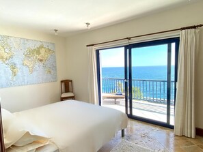 A bedroom with a bed, a chair, a map on the wall, and a balcony with a view of the sea. - A Wonderful Frontline Villa to Watch the Boats Go By! (Yaiza)