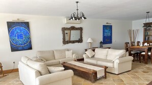 A living room with beige sofas, a wooden coffee table, and a dining area with a wooden table and chairs. - A Wonderful Frontline Villa to Watch the Boats Go By! (Yaiza)