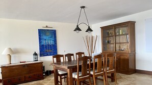 A dining area with a wooden table and chairs, a cabinet with glass doors, and a blue abstract painting on the wall. - A Wonderful Frontline Villa to Watch the Boats Go By! (Yaiza)