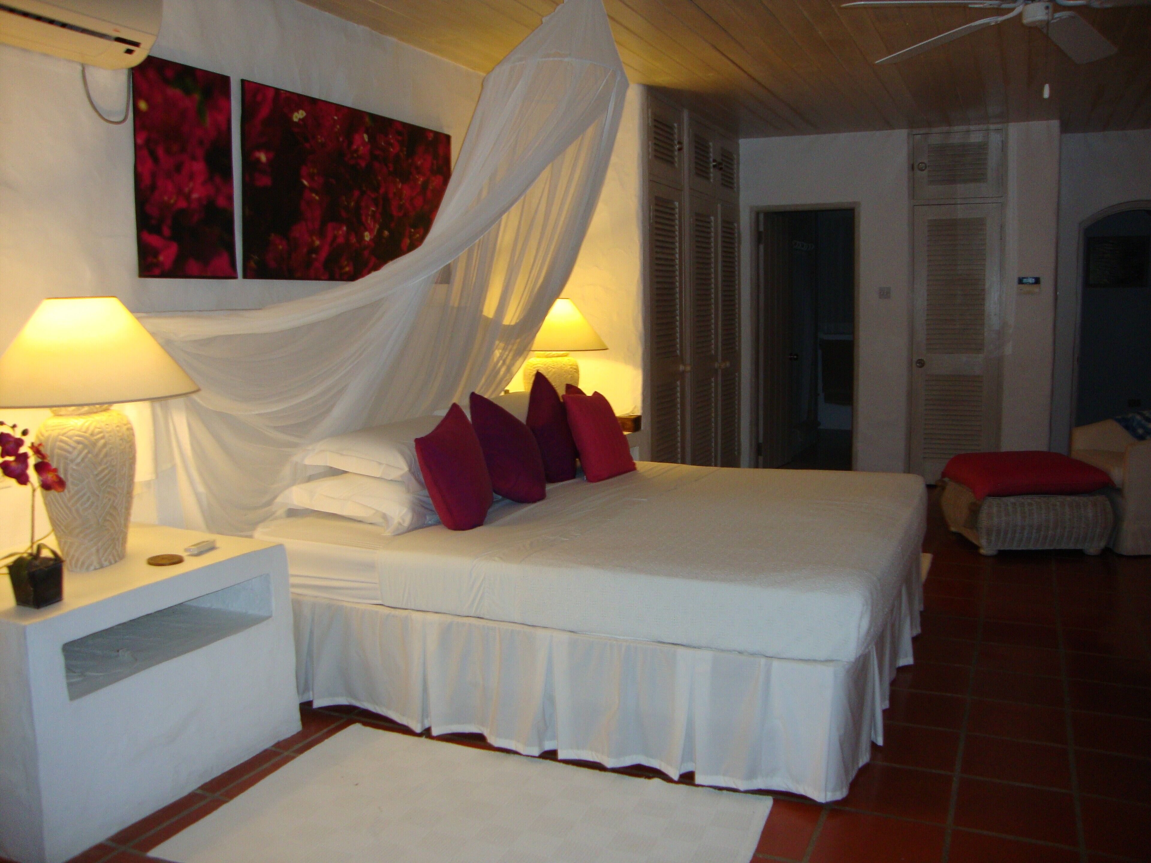 Un dormitorio con una cama, dos mesitas de noche, una lámpara y un aire acondicionado instalado en la pared.